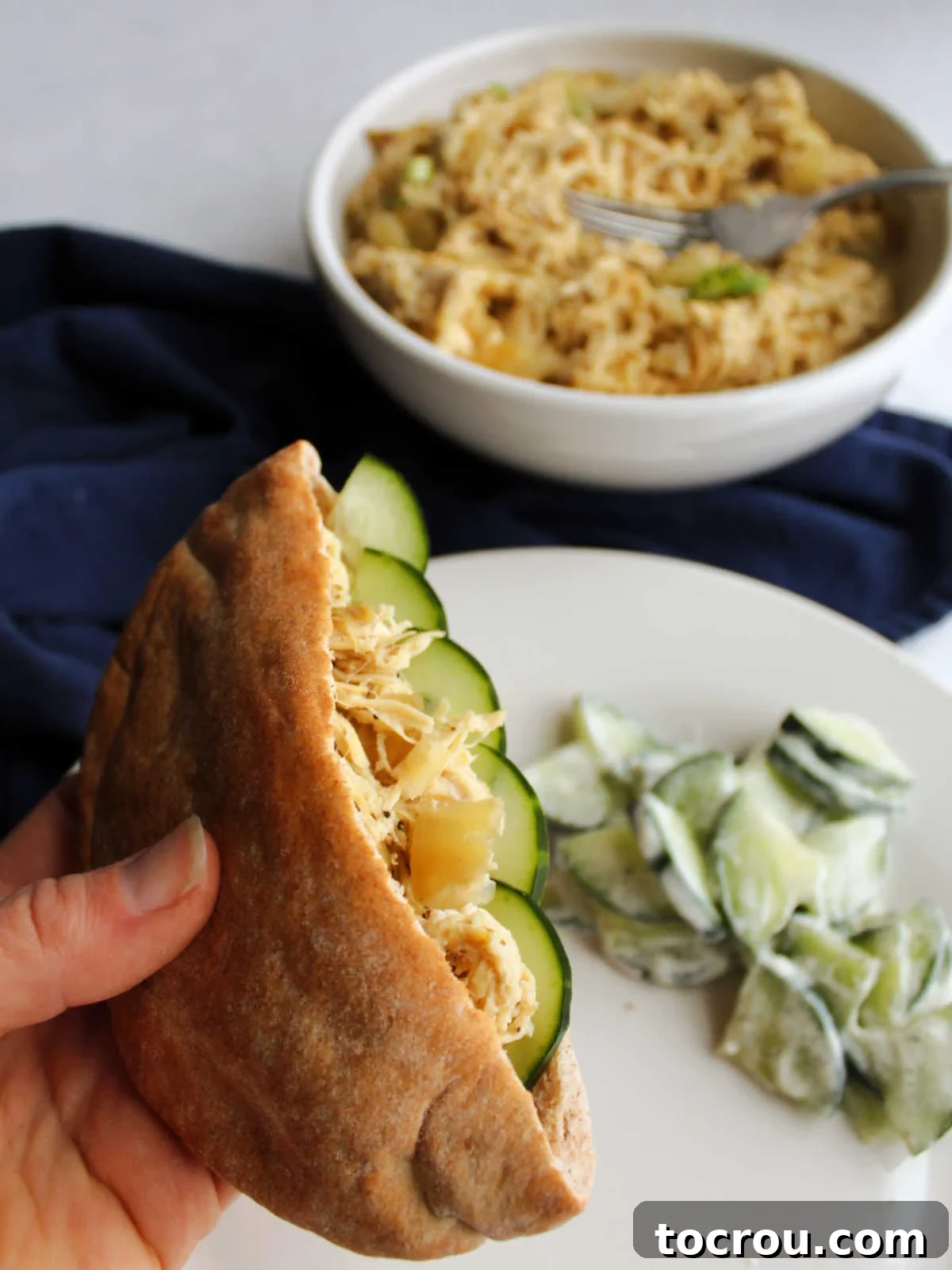 Greek Chicken Pita with Cucumber Salad Whole wheat pita pocket filled with shredded Greek yogurt chicken and cucumber slices, served alongside a creamy cucumber salad for a complete meal.