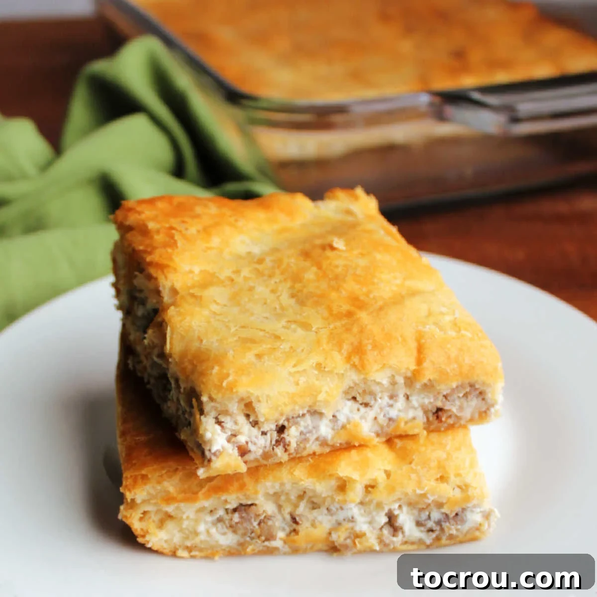 Savory Sausage Cream Cheese Puffs 2 Two squares of golden crescent bars with a creamy sausage and cream cheese filling visible between the flaky layers.