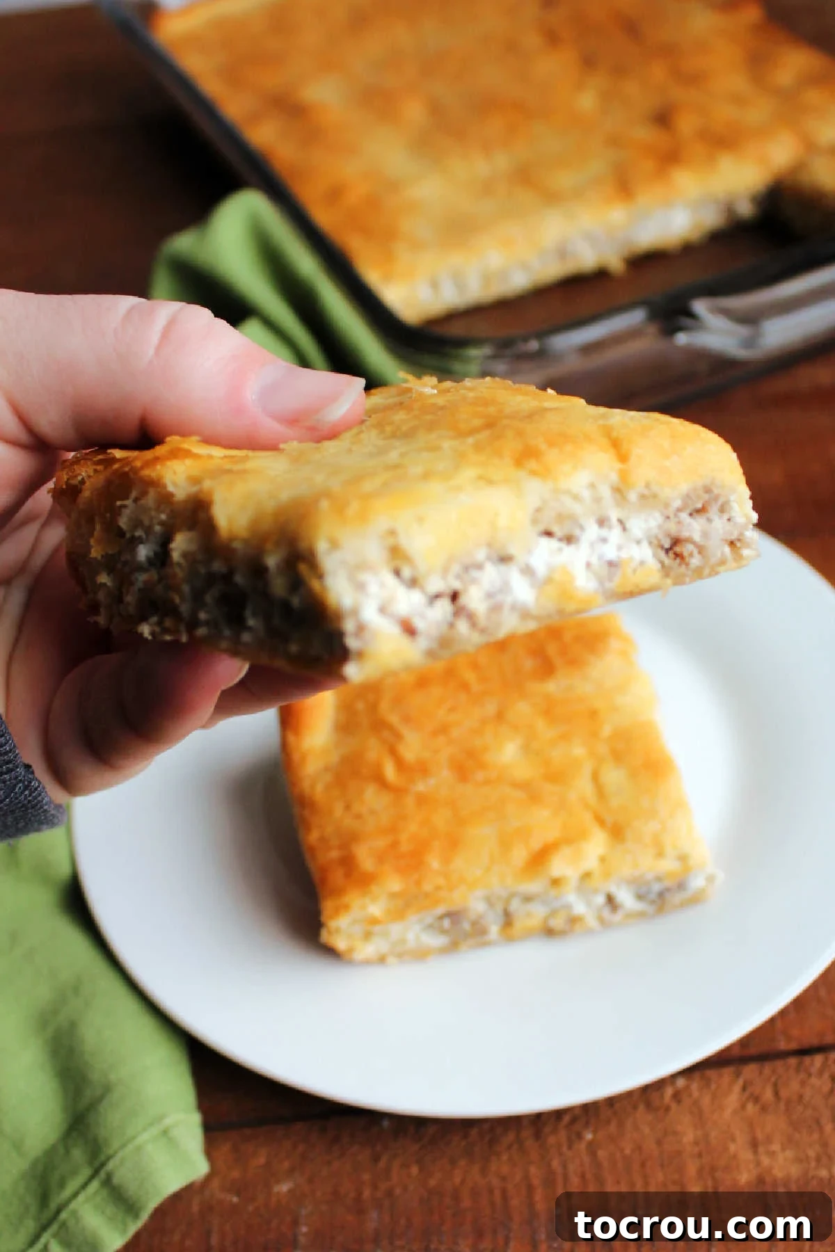 Savory Sausage Cream Cheese Puffs 3 Hand holding cream cheese and sausage crescent bar showing cheesy sausage filling.