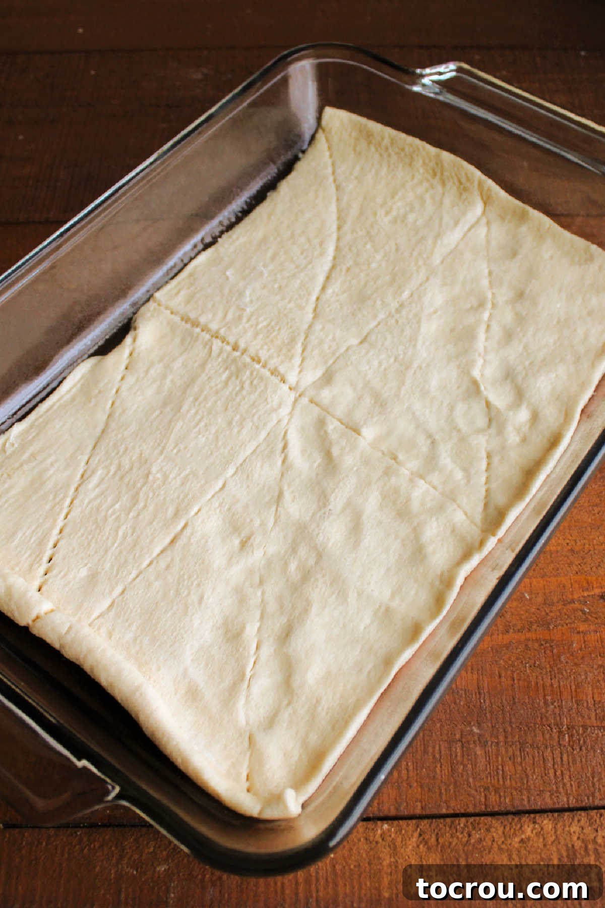 Savory Sausage Cream Cheese Puffs 5 Sealing the seems on crescent dough and pressing it into a 9x13-inch pan.