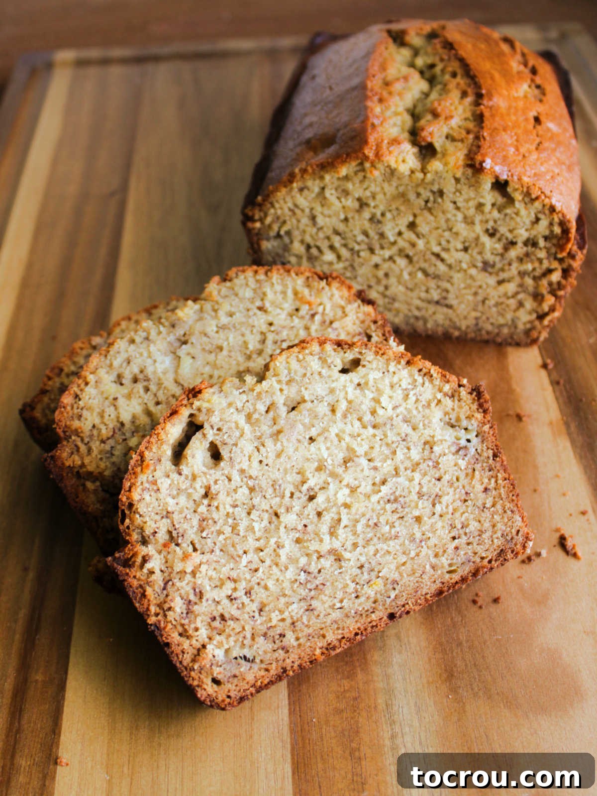 Close-up of a sliced banana bread, revealing its soft, moist interior dotted with banana pieces and a beautiful golden exterior crust.