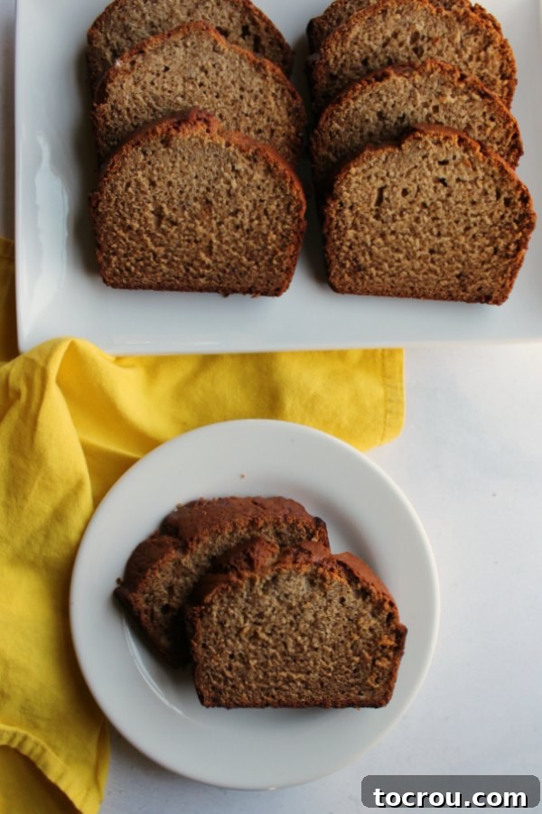 Two slices of moist banana bread arranged on a small plate, with more slices visible on a larger platter in the background, inviting a delightful indulgence.