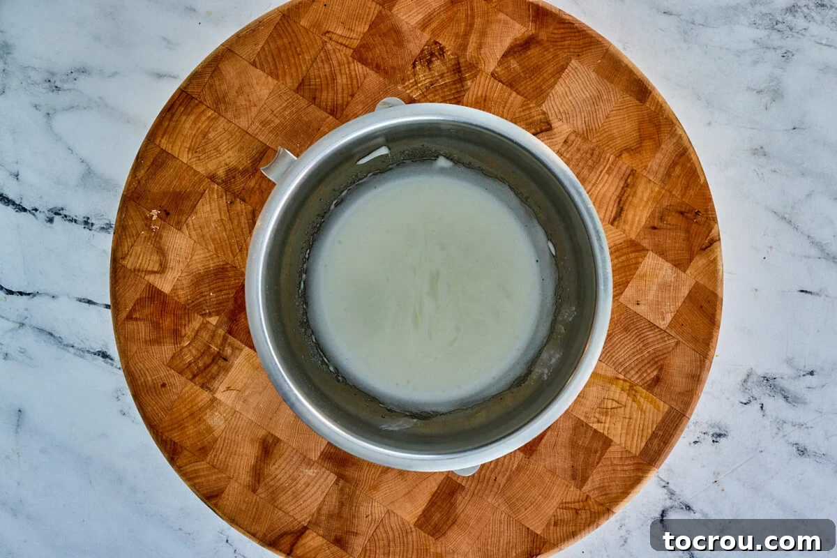 A frothy mixture of egg whites and cream of tartar in a mixer bowl, indicating it's ready for the gradual addition of sugar to create a luscious meringue.