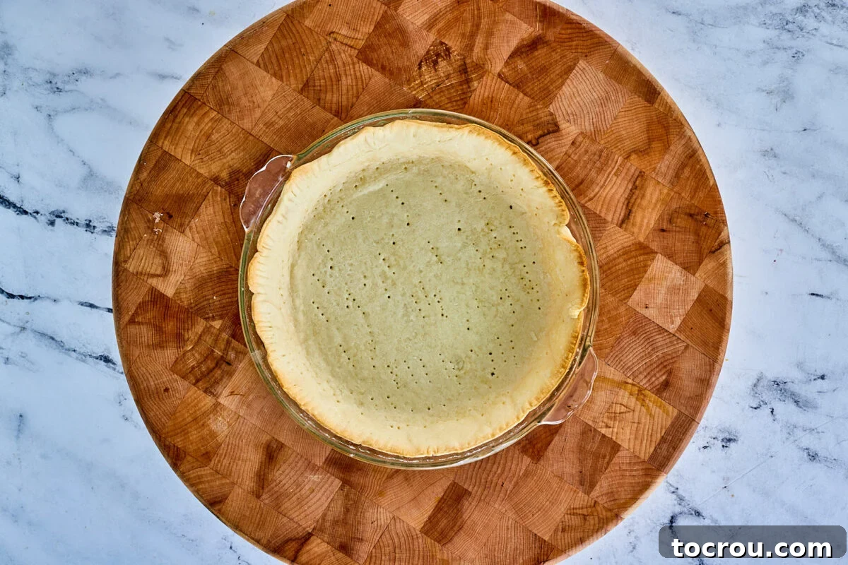 A beautifully baked pie shell, golden brown and crisp, with the parchment and weights removed, awaiting its delicious filling.