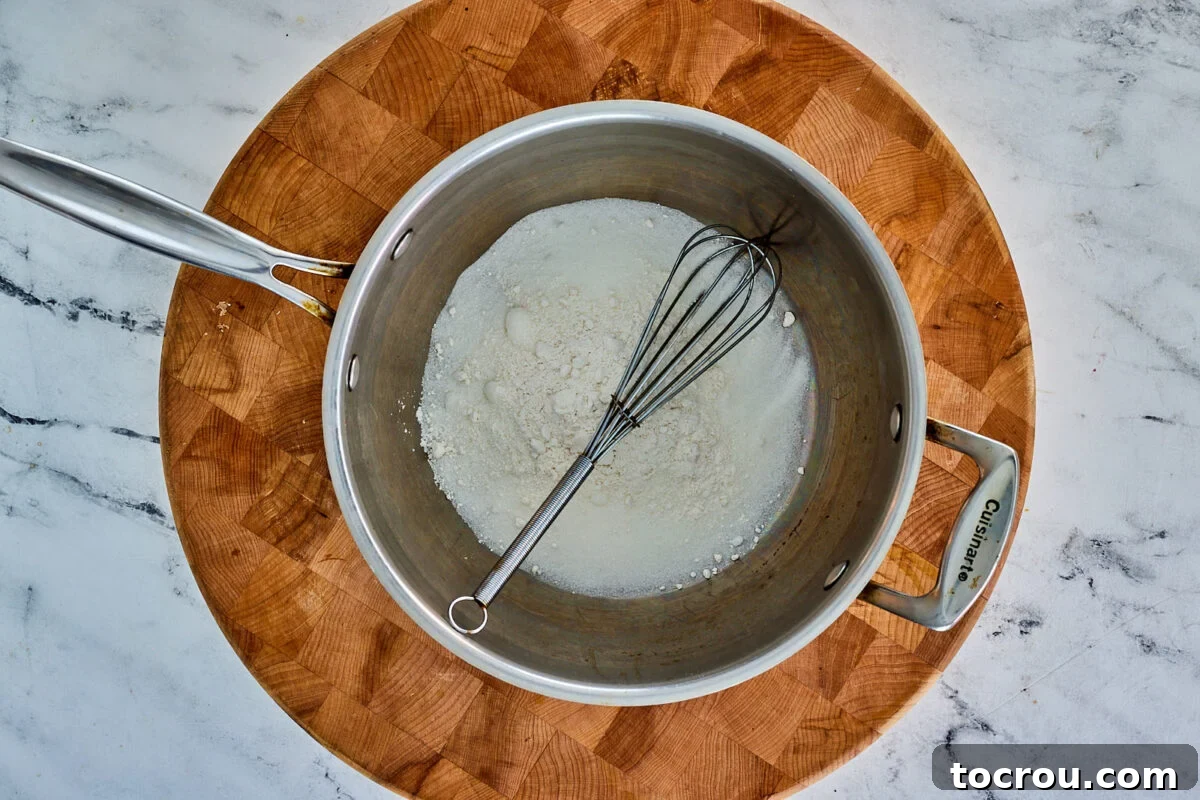 Granulated sugar and all-purpose flour expertly whisked together in a saucepan, forming the base for the pie filling.