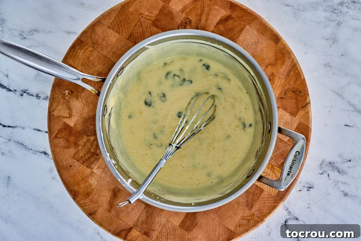 A rich custard, made from sour cream, egg yolks, and the sugar mixture, gently simmering in a saucepan with plump raisins carefully mixed in.