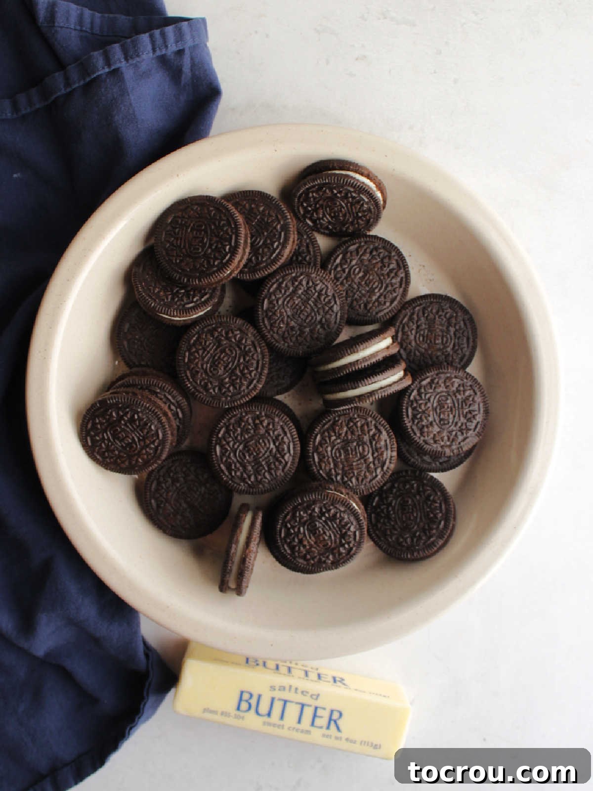 Ingredients for a no-bake chocolate pie crust: a package of Double Stuf Oreos and a stick of butter, highlighting the simplicity.