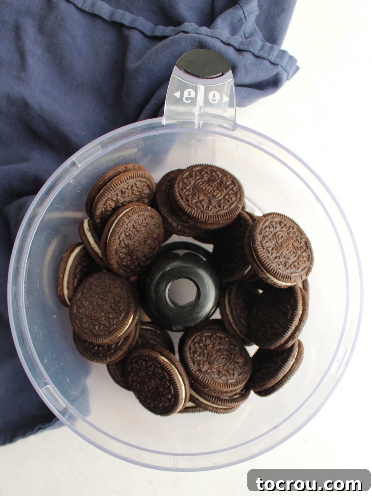 Whole Oreo cookies placed inside a food processor bowl, ready to be transformed into fine crumbs for the pie crust.