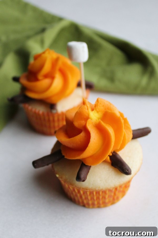 two campfire cupcakes with a mini marshmallow on a stick ready to be roasted