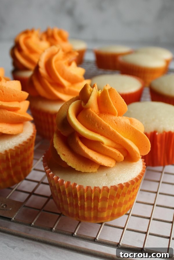 orange and yellow swirled frosting piped on top of semi-homemade white cupcakes