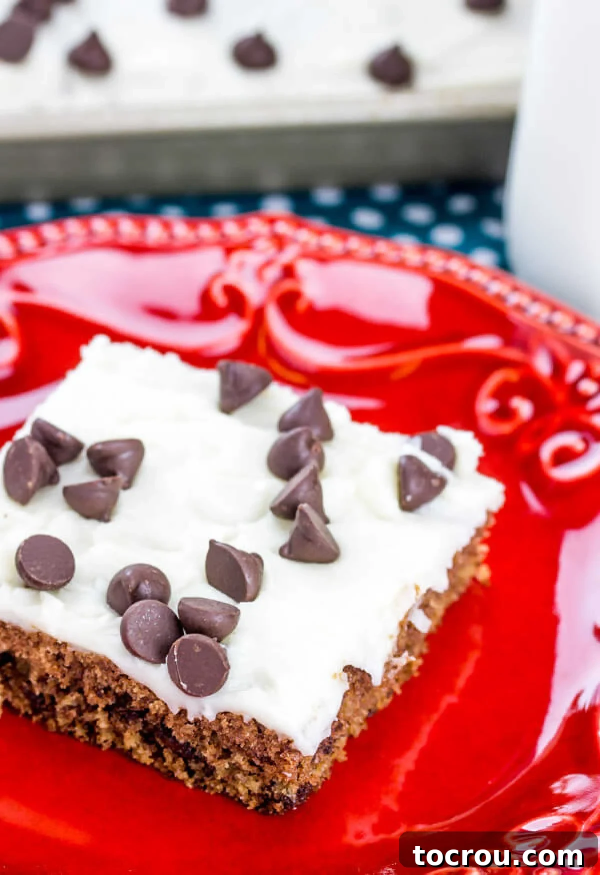 The Ultimate Chocolate Chip Cookie Dough Texas Sheet Cake 6 piece of cookie dough sheet cake with smooth white icing and chocolate chips on top.