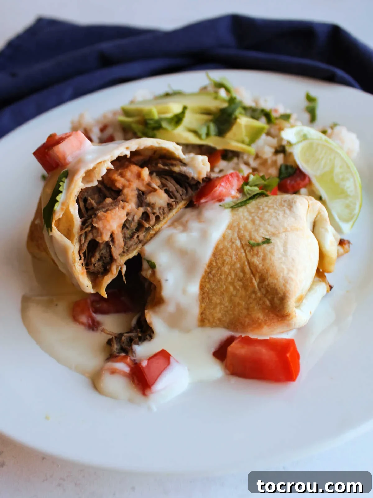 Crispy Baked Barbacoa Chimichangas 2 Crispy venison barbacoa chimichanga topped with creamy white cheese sauce, diced fresh tomatoes, and cilantro, served with refried beans.