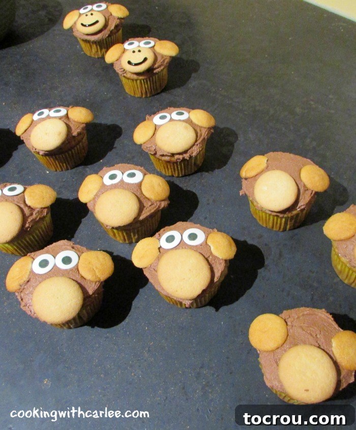 Partially decorated monkey cupcakes with candy eyes added, beginning to form cute expressions.