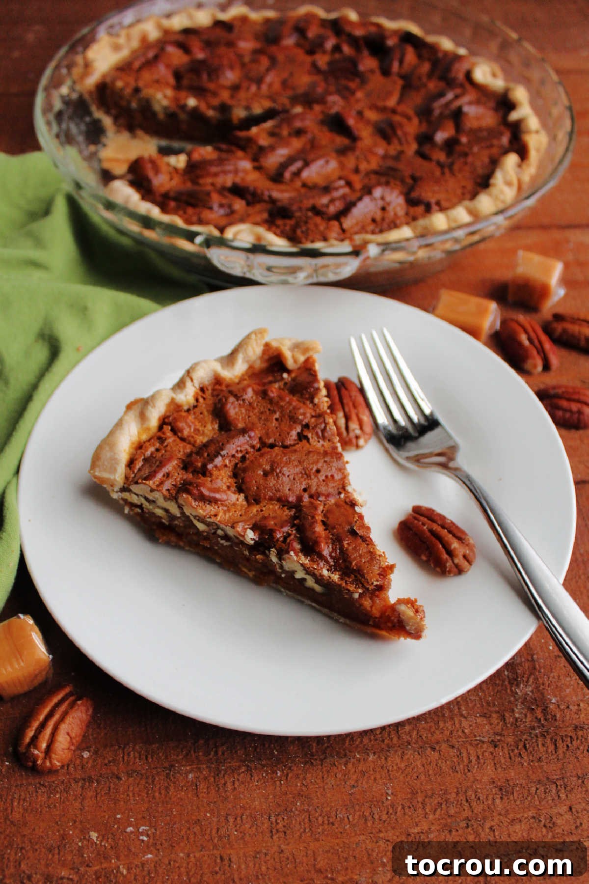 Golden Caramel Pecan Delight 10 Slice of caramel pecan pie served with remaining pie in the background.