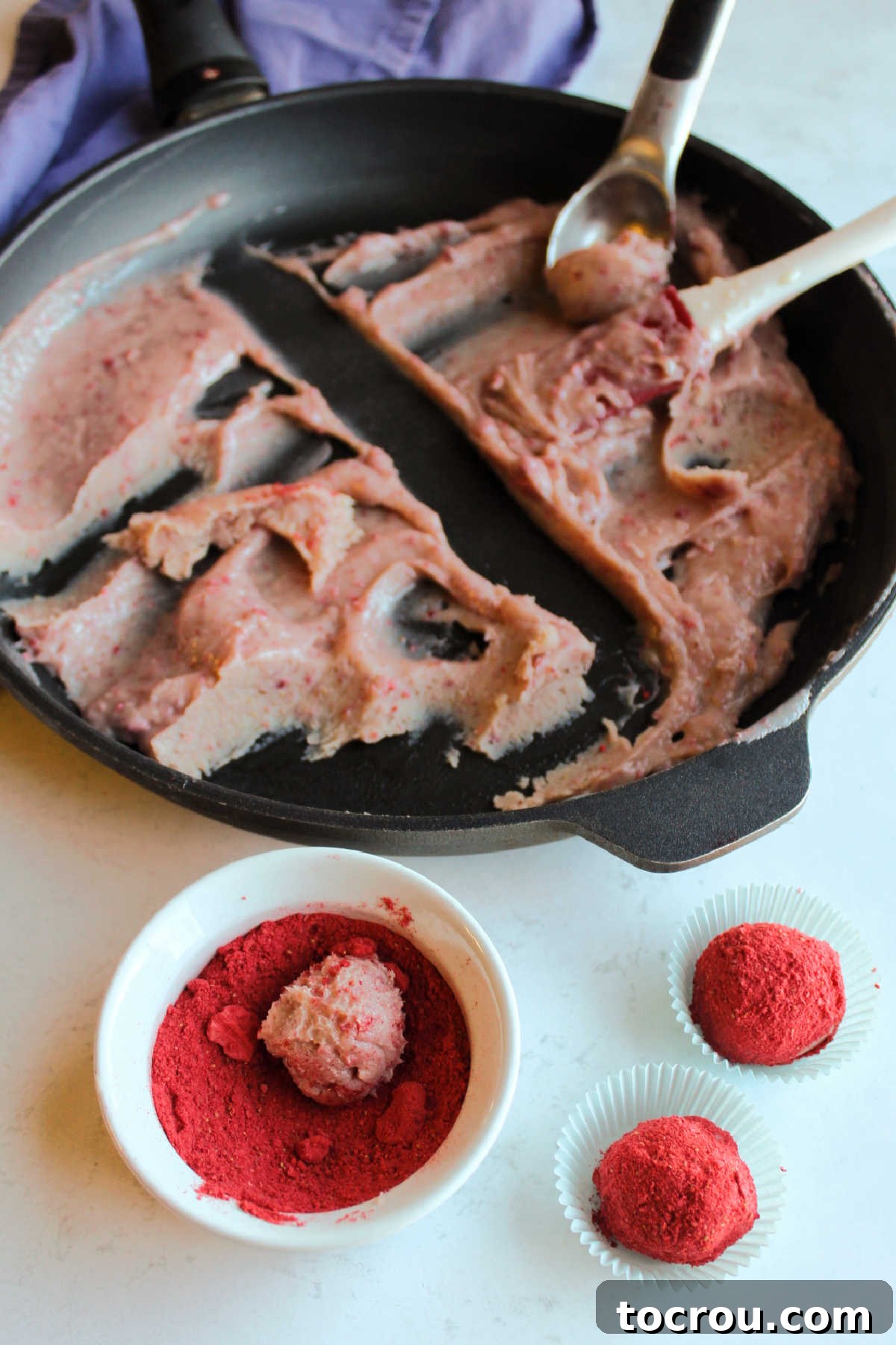 Rolling cooled pink strawberry brigadeiro mixture into balls and then coating them in red strawberry powder.