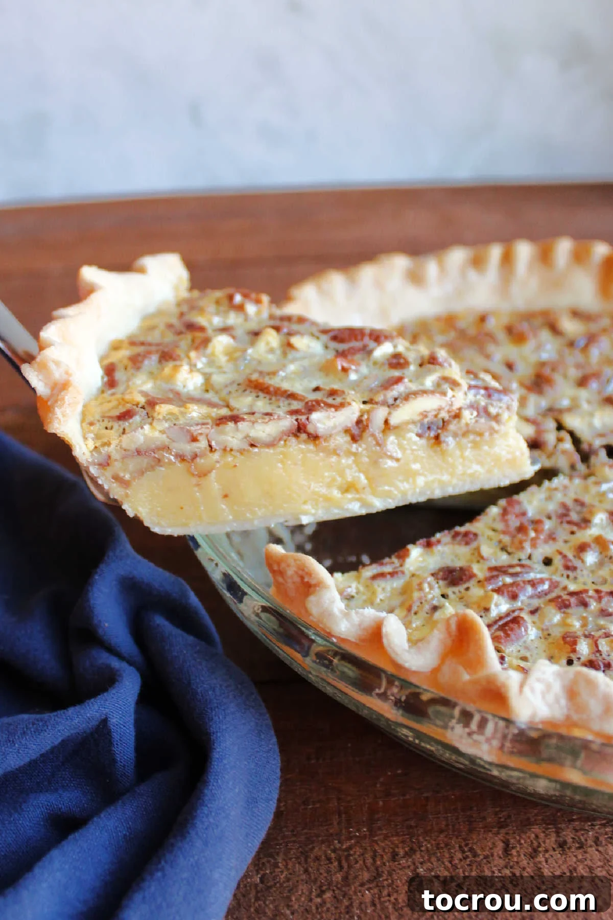 Lifting first slice of cooled condensed milk pie out of the pan, showing smooth creamy center.