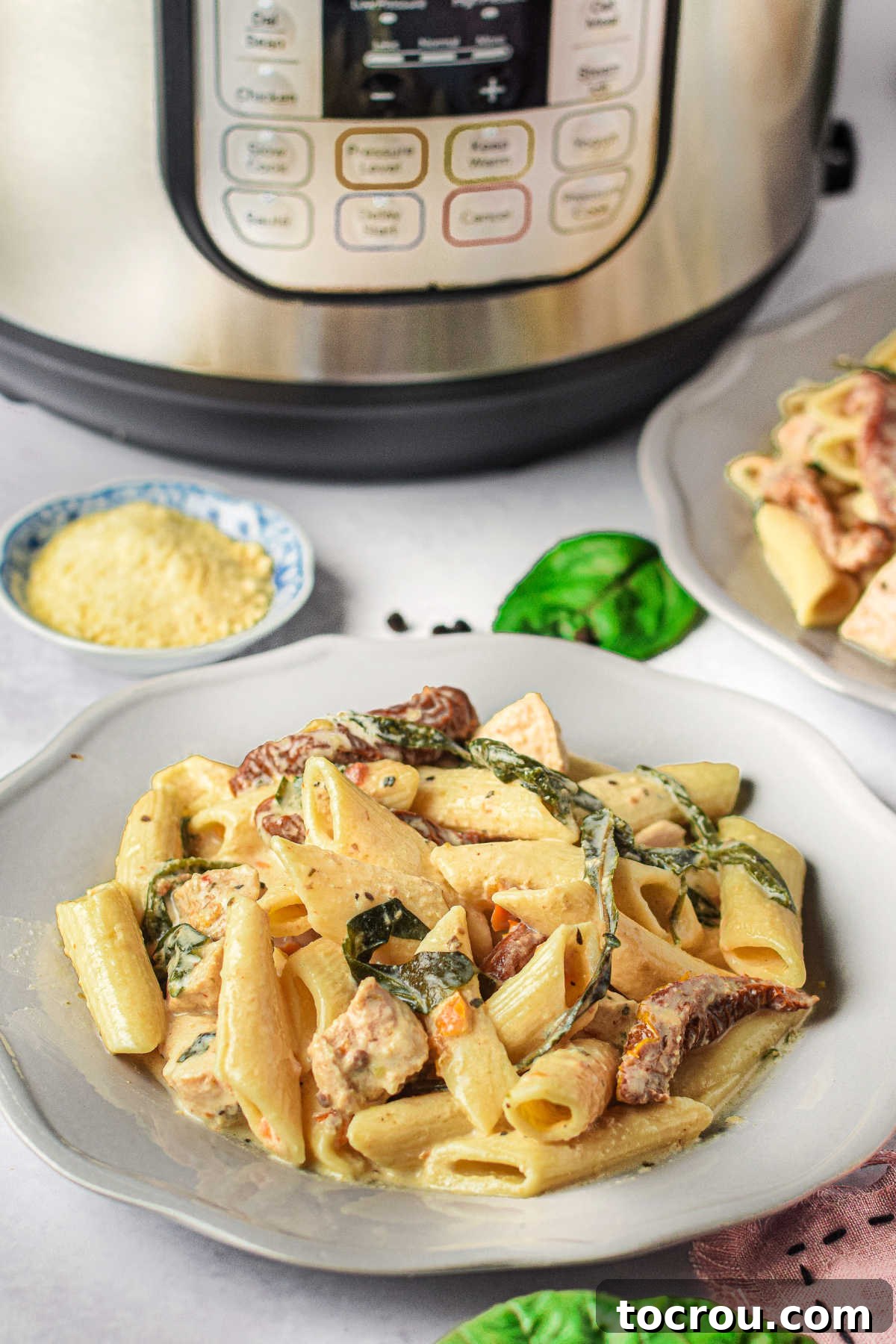 Plate of creamy Tuscan chicken pasta served in front of an Instant Pot.