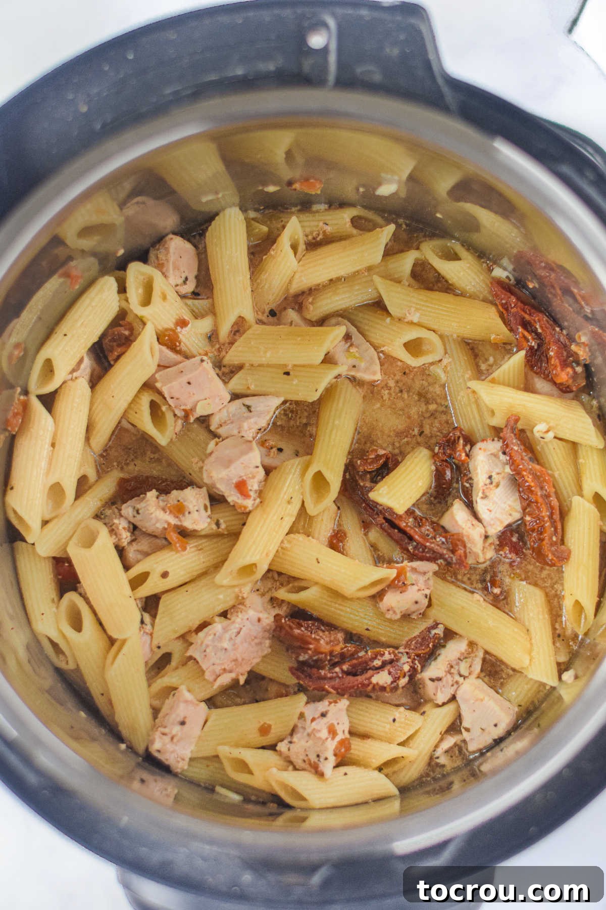 Cooked chicken and pasta mixture in the Instant Pot after pressure release, ready for final additions.