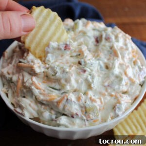A ruffled potato chip scooping a generous amount of cheesy dill pickle dip