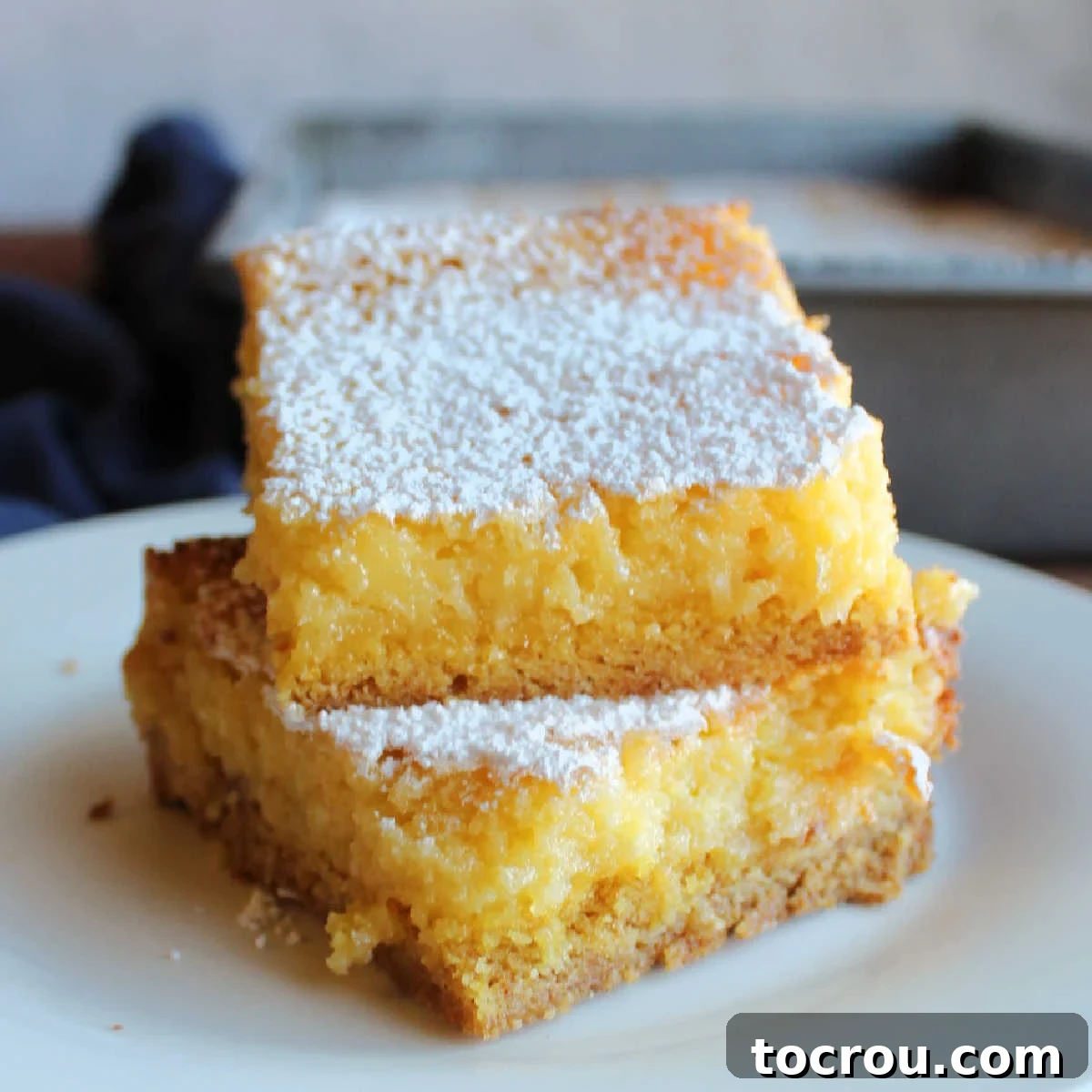 Zesty Lemon Chess Bars 2 Stack of lemon gooey butter cake bars with cakey crust and gooey cream cheese, lemon and butter topping.