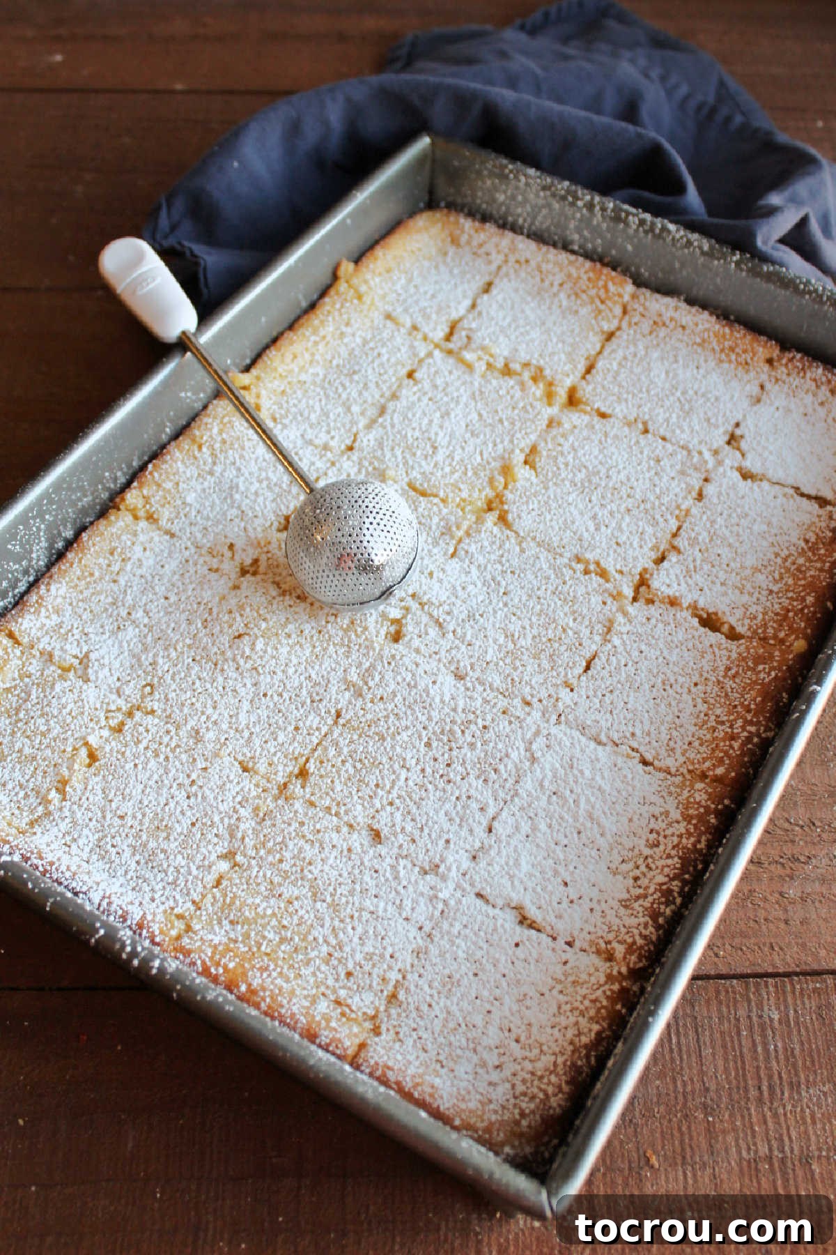Zesty Lemon Chess Bars 7 Dusting powdered sugar on cut lemon chess squares.