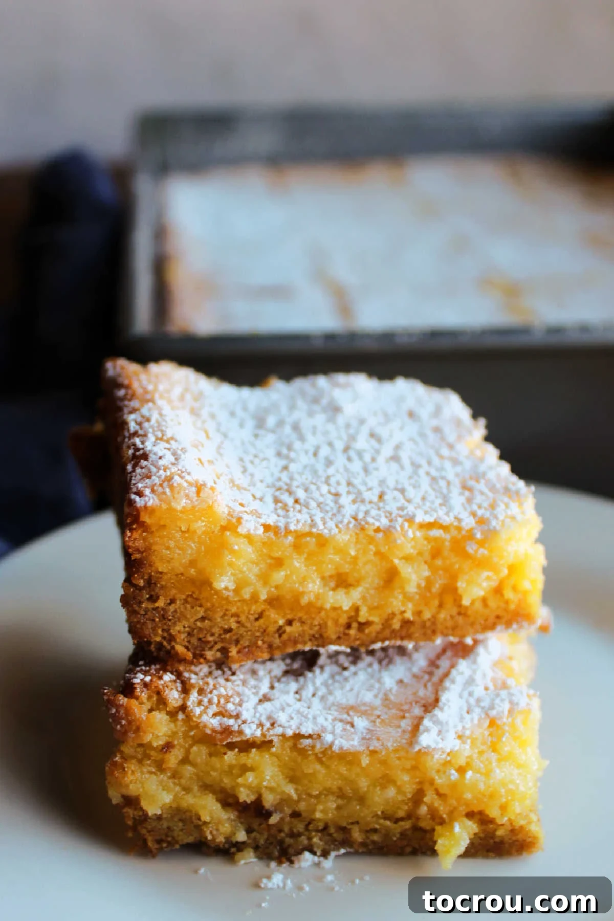 Zesty Lemon Chess Bars 8 Stacked lemon chess bars topped with powdered sugar, ready to eat.