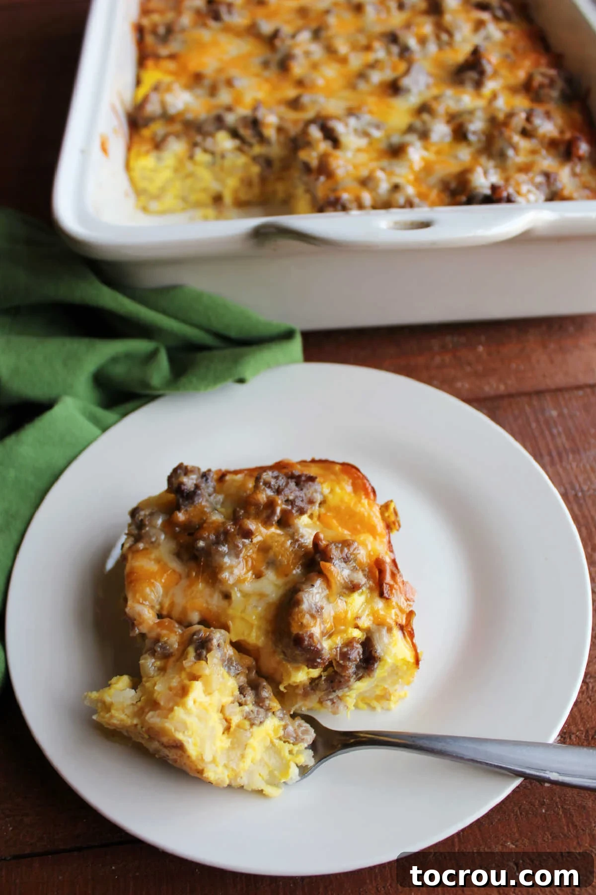 Perfect Bite of Casserole A close-up of a bite of hashbrown egg casserole on a fork, showing the layers of egg, sausage, hashbrowns, and cheese, ready for a delicious taste.
