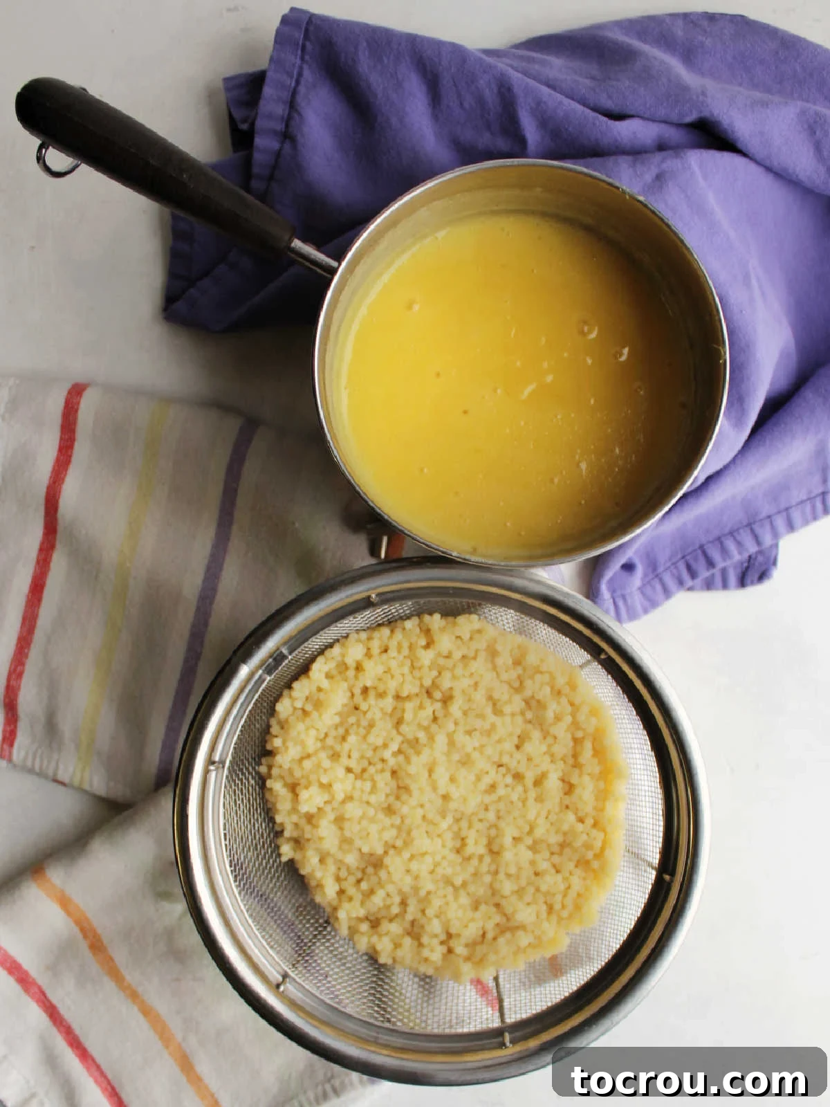 Strainer of cooked pepe pasta next to saucepan with cooked fruit juice custard mixture ready to be stirred together.