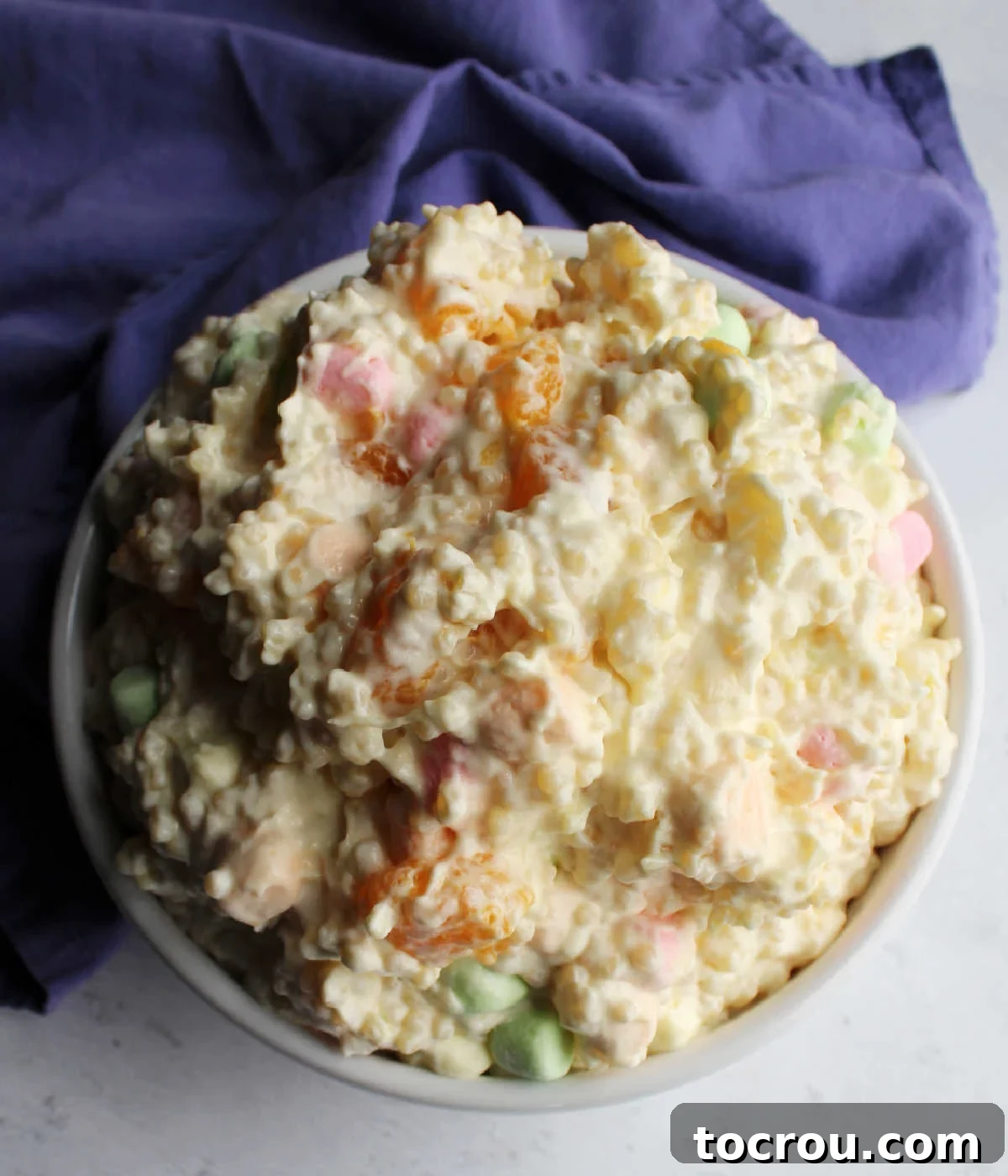 Looking down on big bowl of frog eye salad with pastel marshmallows.