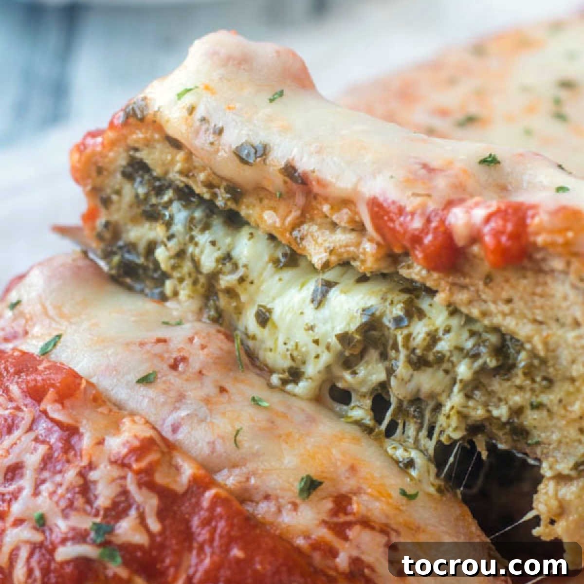 Delicious Chicken Parmesan Meatloaf Showing melted cheese and pesto inside marinara and cheese topped chicken meatloaf.