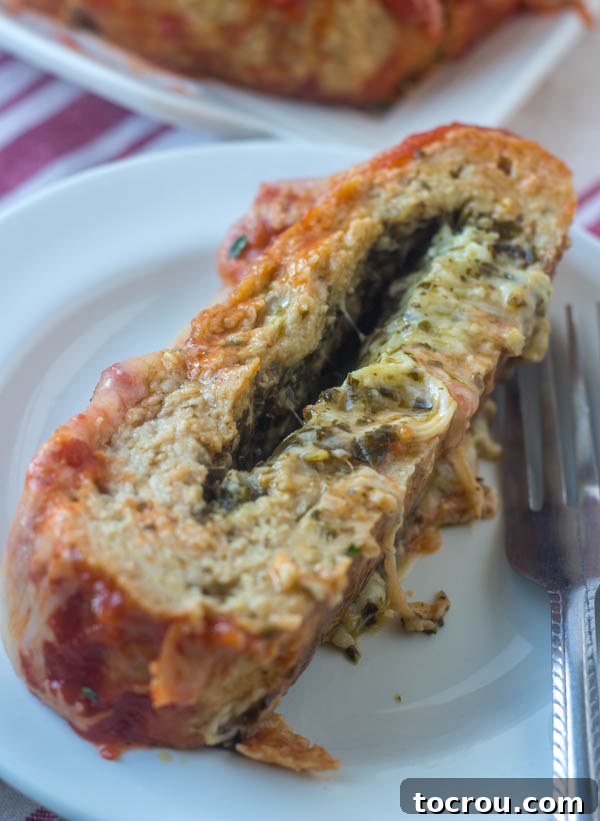 Pesto and Cheese Stuffed Meatloaf Slice of cheese and pesto stuffed chicken meatloaf, ready to eat.