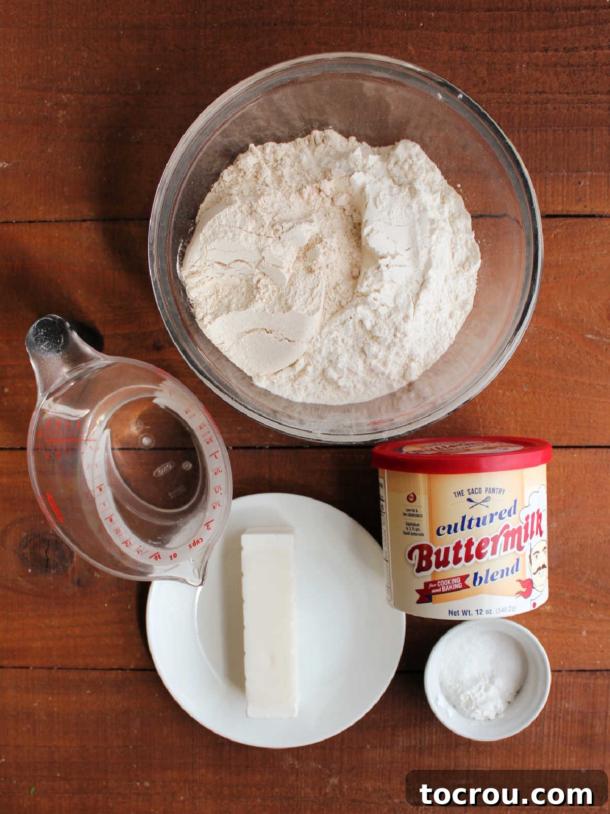 Lard Biscuit Ingredients Laid Out Ingredients including flour, buttermilk powder, baking powder, baking soda, salt, lard and cold water ready to be made into biscuits.