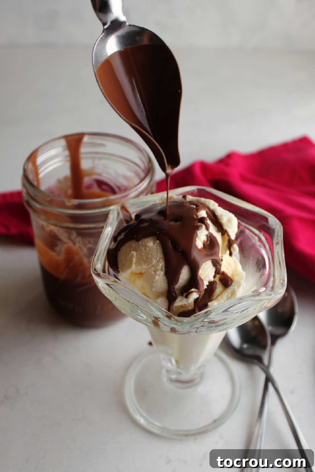 Drizzling Chocolate Magic Shell Spoon drizzling warm chocolate magic shell over a bowl of vanilla ice cream, creating a hard shell.