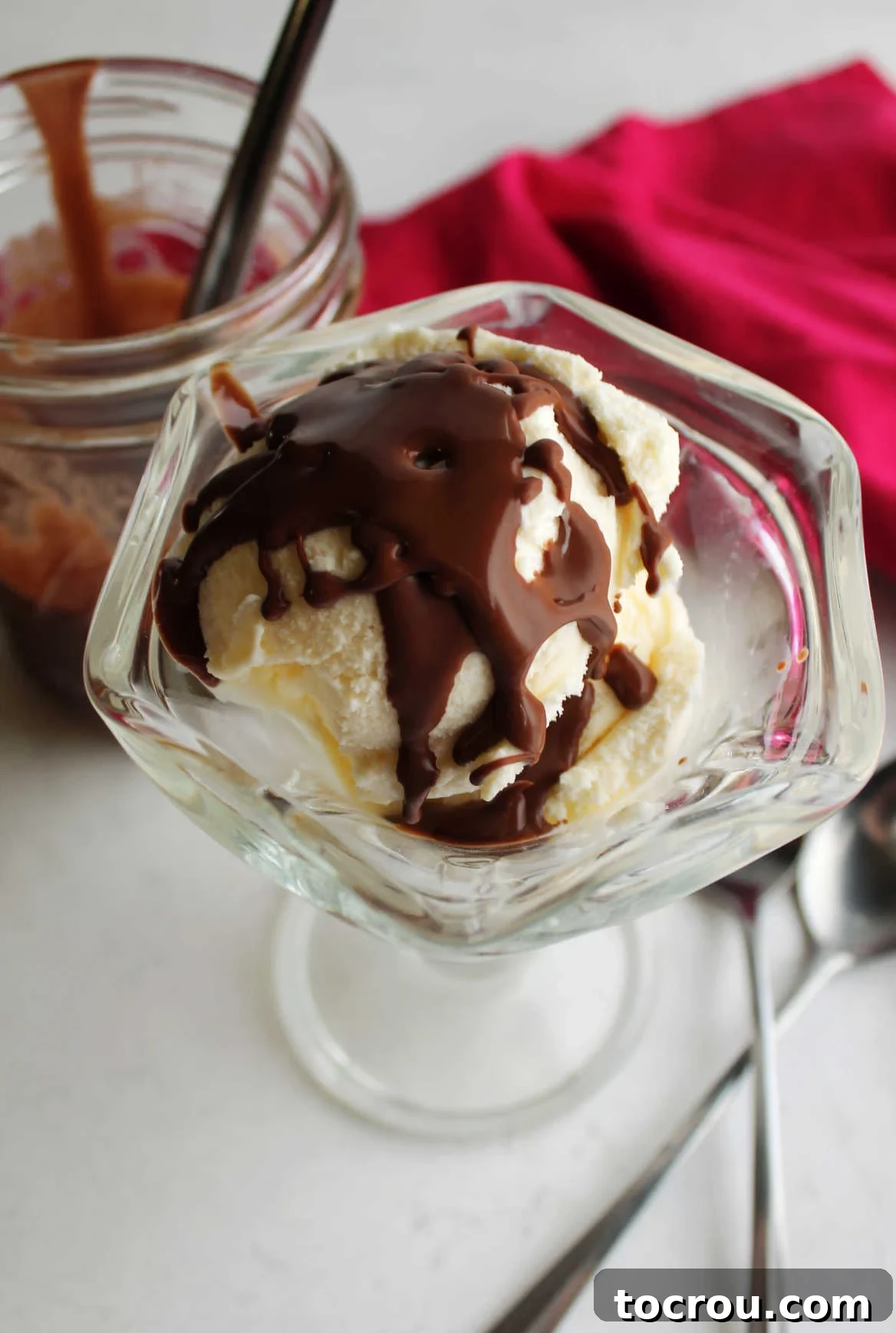 Vanilla Ice Cream with Magic Shell Topping Glass sundae dish filled with vanilla ice cream topped with homemade chocolate magic shell, showing a satisfying crack.