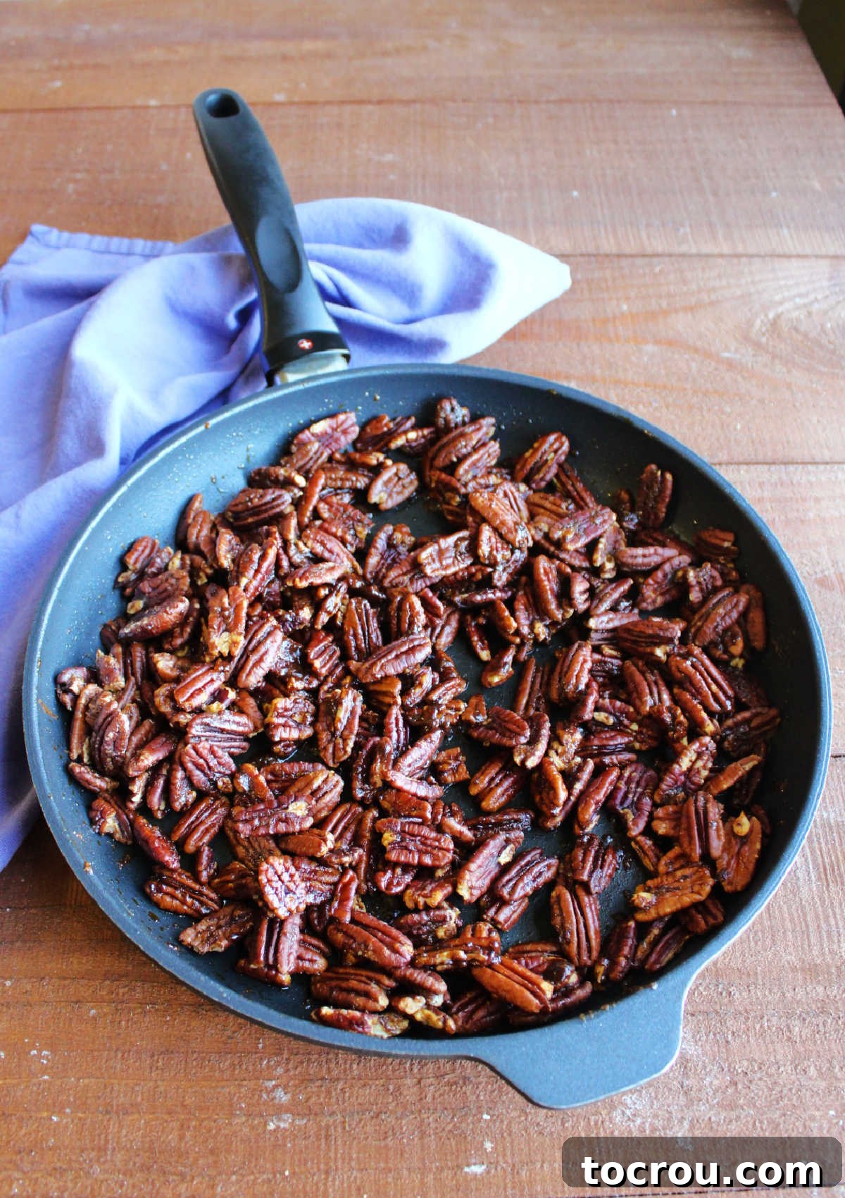 Freshly Baked Spiced Pecans A large skillet filled with freshly baked, glistening spiced pecans, just removed from the oven.
