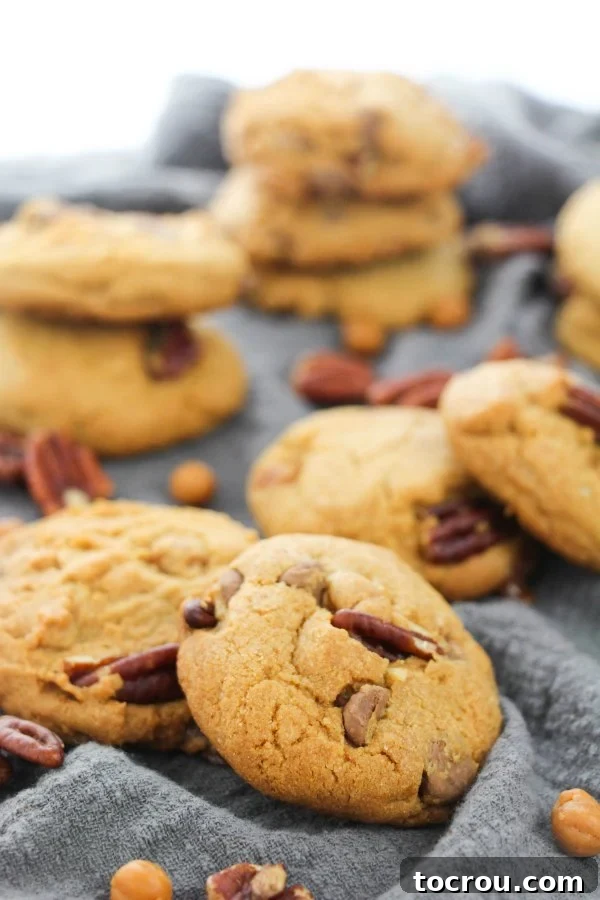 A stack of golden brown Turtle Cookies, glistening with melted chocolate, soft caramel, and toasted pecans, waiting to be enjoyed. The rich combination makes these cookies truly special.
