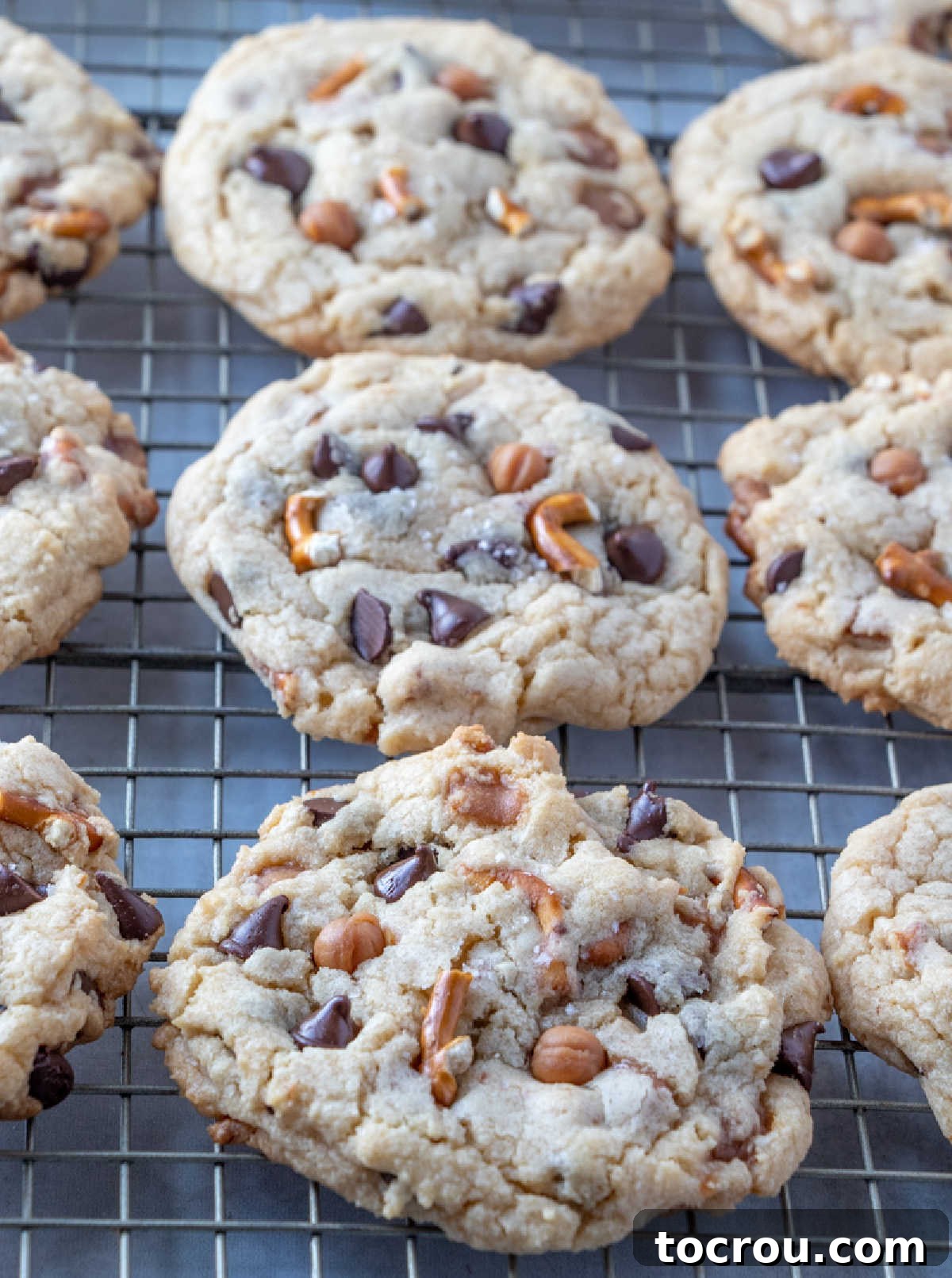 Kitchen sink cookies with caramel, chocolate chips and pretzel bits on cooling rack.