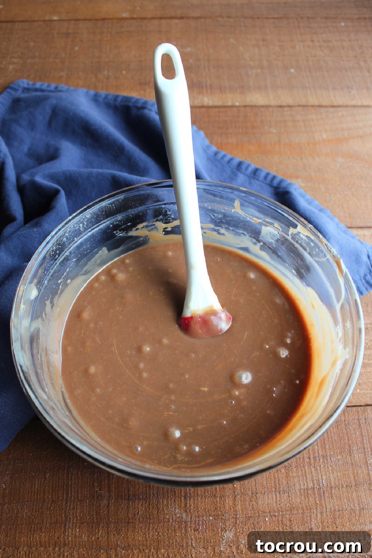 Smooth Chocolate Peanut Butter Fudge A glass mixing bowl filled with a smooth, glossy, and perfectly melted chocolate peanut butter fudge mixture after being heated in the microwave and stirred until combined.