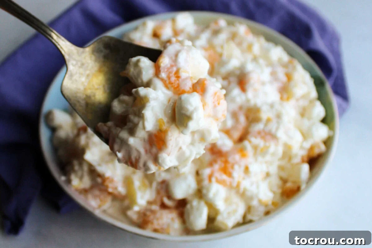 Antique serving spoon with creamy 5 cup salad with fruit, coconut, and marshmallows.