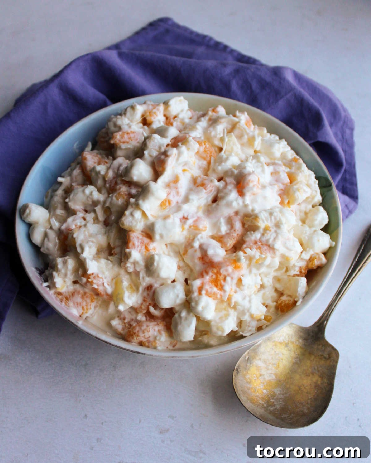 Refrigerated five cup salad showing how the dressing looks thicker, ready to eat with antique serving spoon nearby.