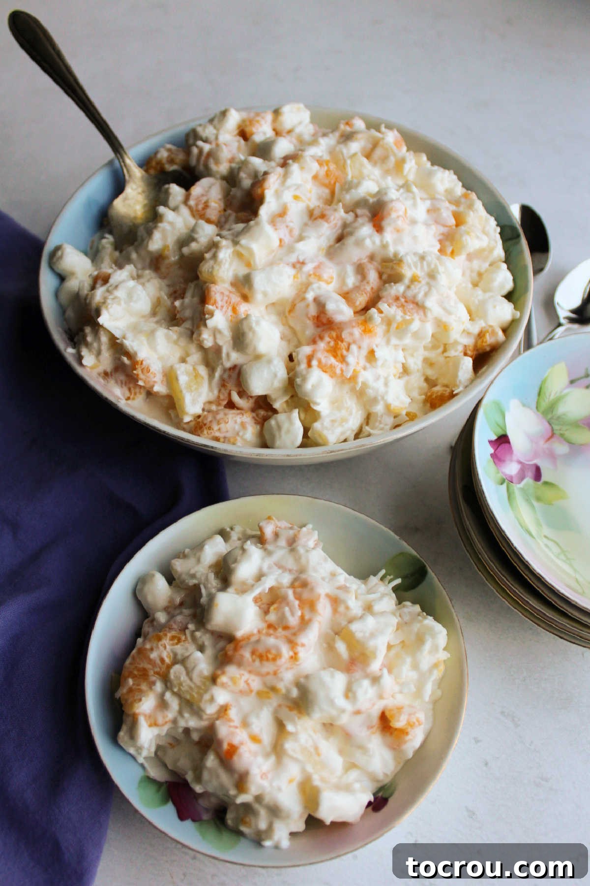 Serving of five cup salad in antique china with big bowl of salad in the background.