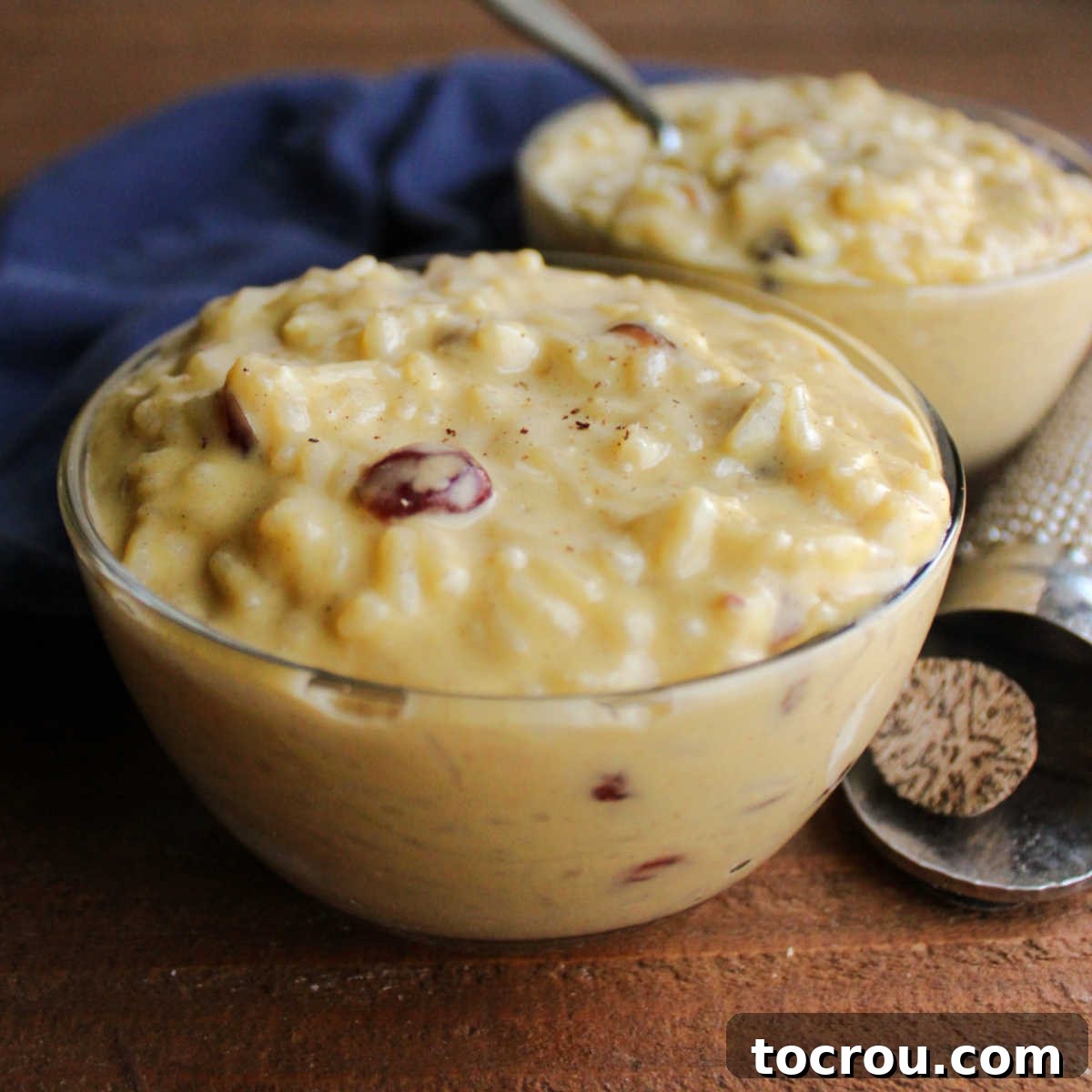 Creamy Evaporated Milk Rice Pudding Close up of small glass bowls filled with creamy rice pudding with cinnamon, nutmeg and dried cranberries inside.