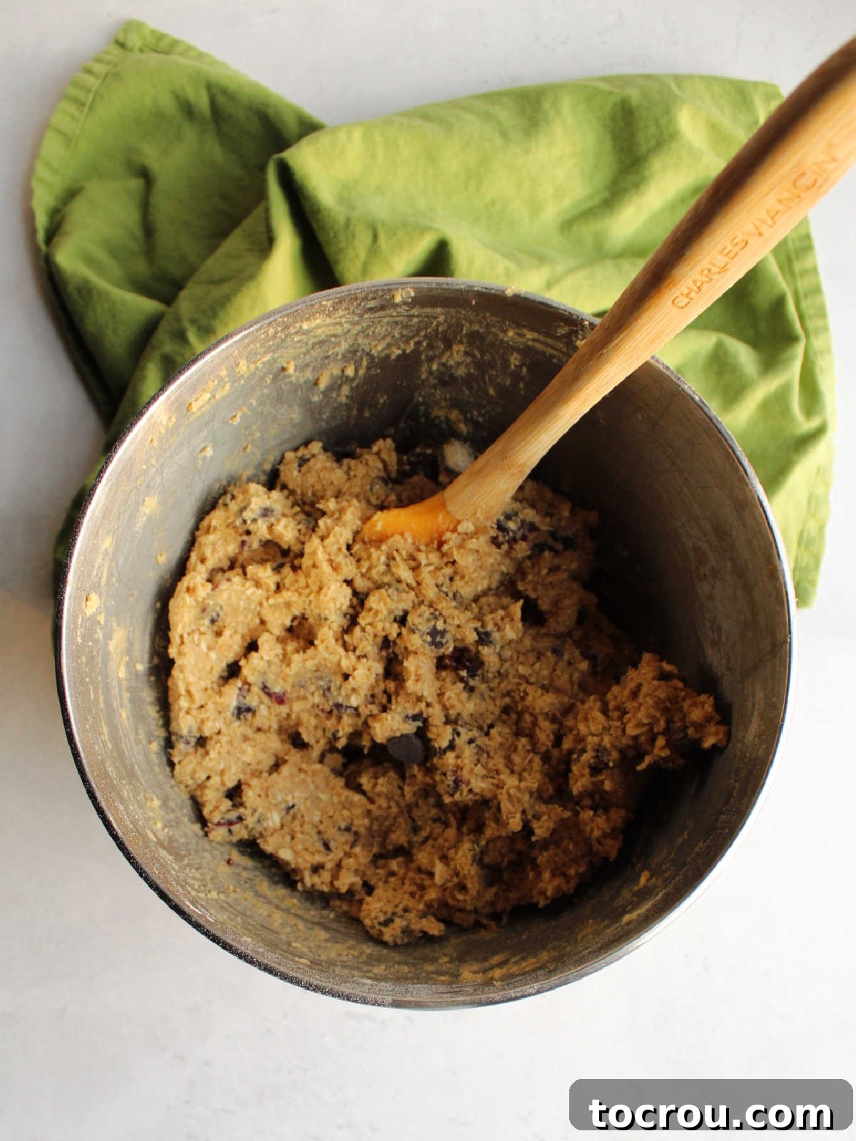 Oatmeal Cinnamon Drop Cookie Dough in Mixer A large mixing bowl filled with creamy, light brown oatmeal raisin cookie dough, ready for baking.
