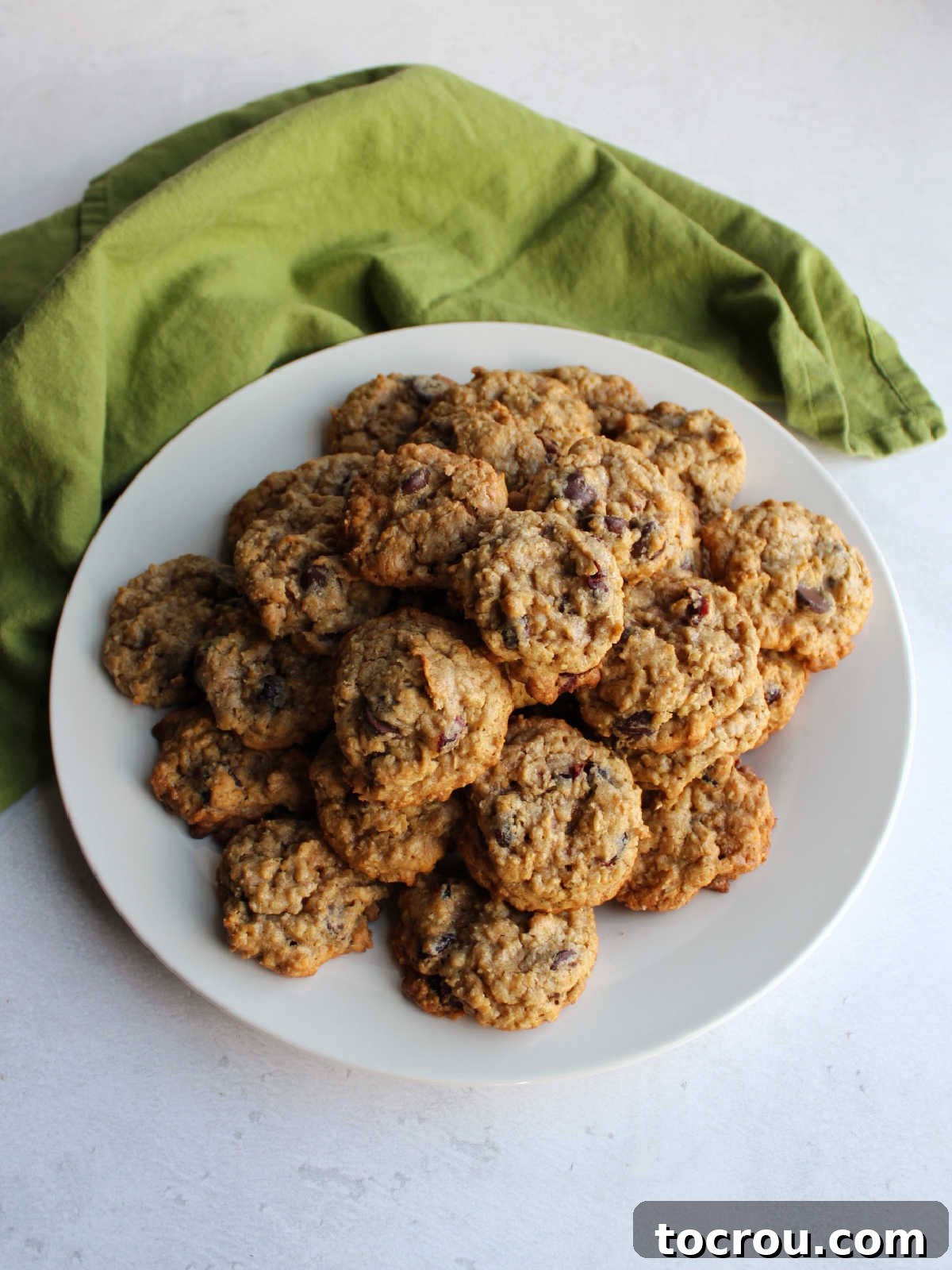 Platter of Homemade Oatmeal Cinnamon Drop Cookies A white ceramic platter generously filled with perfectly baked, golden-brown cinnamon oatmeal raisin cookies, ready for serving.
