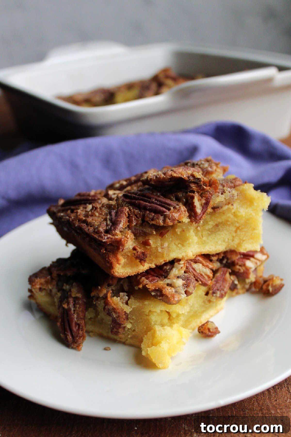 Stacked pieces of pecan pudding cake showing dense center and pecans on top.
