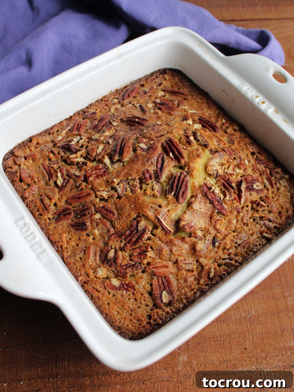 Baked pecan pudding cake with golden top studded with lots of pecans.