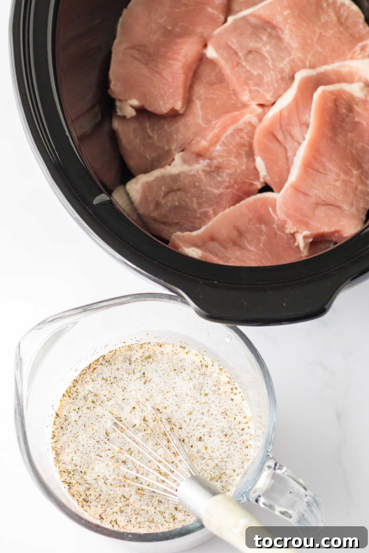 Pork chops in slow cooker next to large measuring cup with sauce mixture.