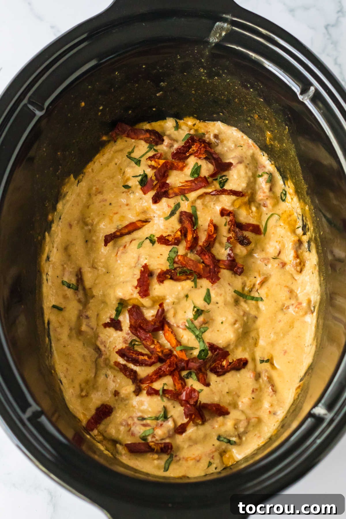 Crockpot insert filled with cooked pork chops and cream sauce, ready to be served.