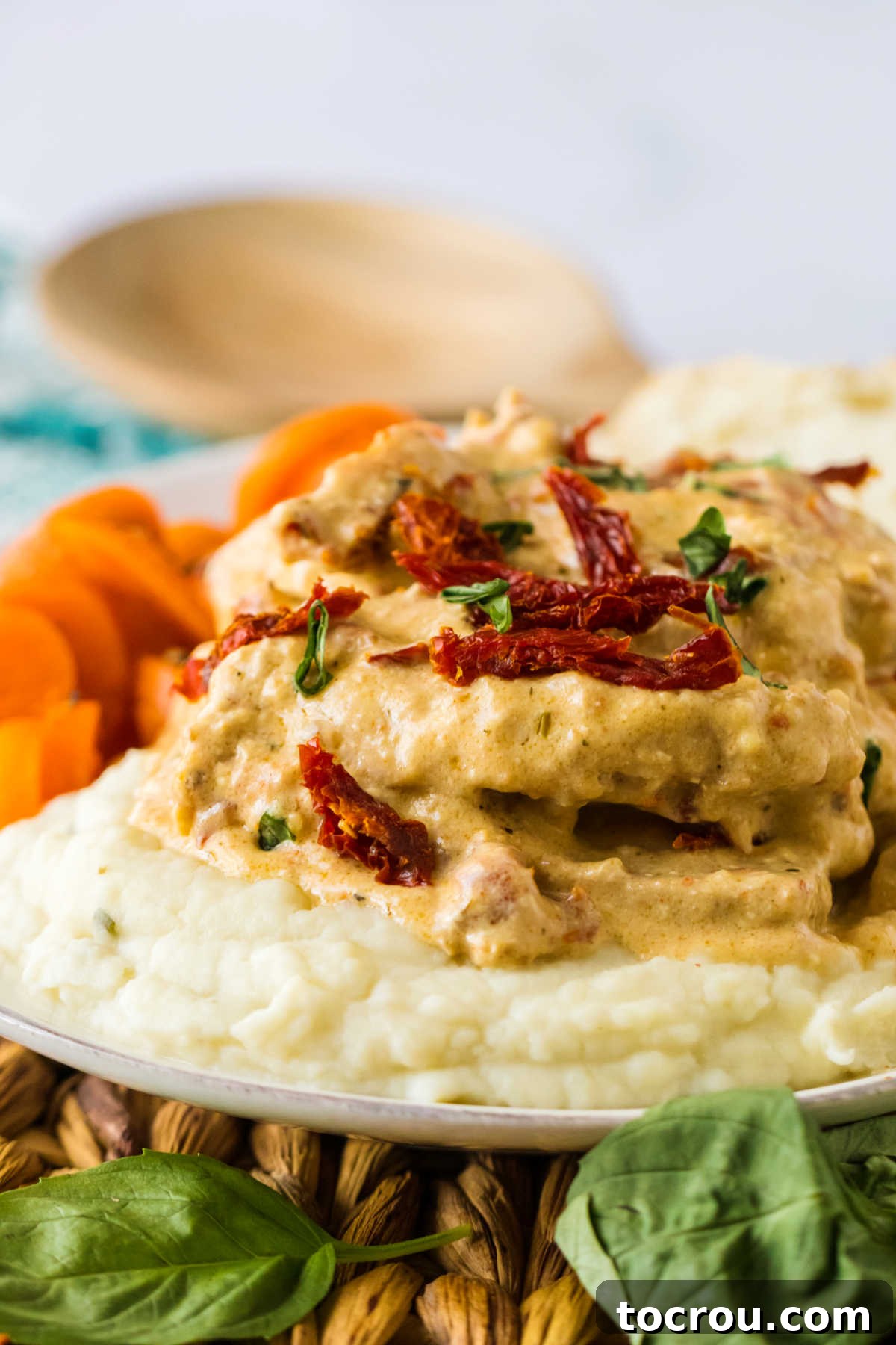 Side view of slow cooker marry me pork chops in creamy sauce on top of a bed of mashed potatoes.