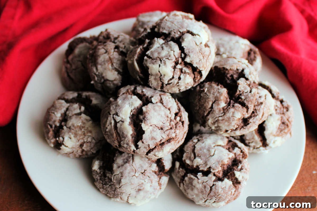 Plate of chocolate gooey butter cookies with rich chocolate center and crackled powdered sugar exterior, ready to eat.
